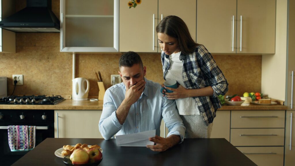 Pareja revisando gastos en la mesa de la cocina